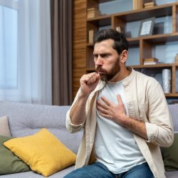 Sick,Mature,Man,Alone,At,Home,Sitting,On,Sofa,Coughing